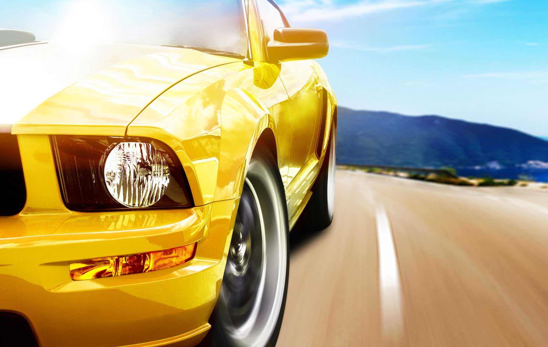 yellow sports car driving down road
