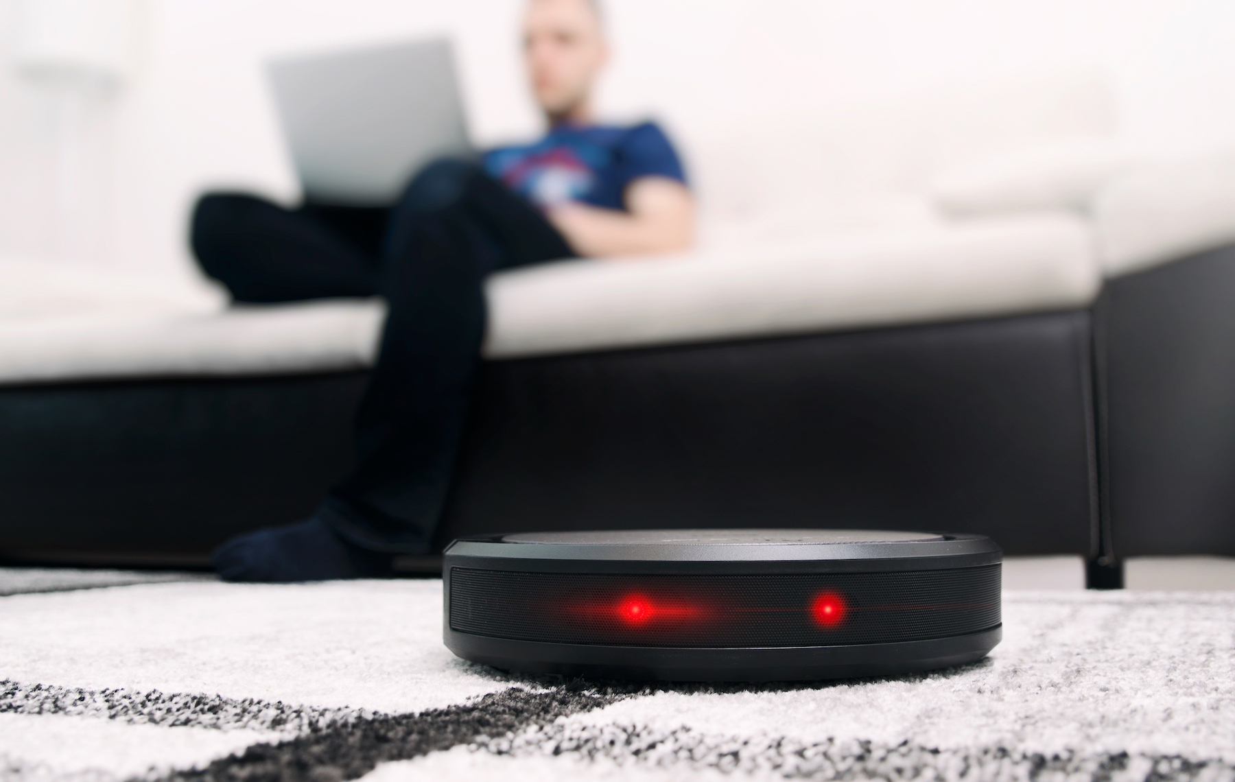 Robotic vacuum on carpet with person in background