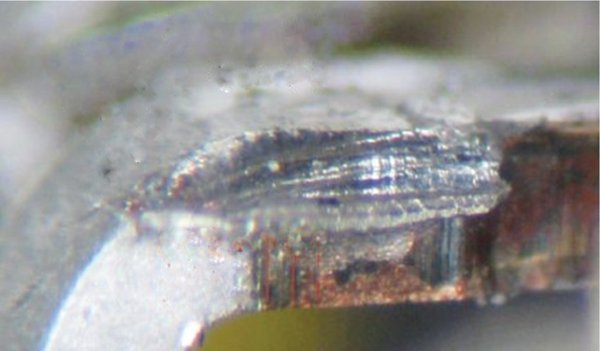 Figure A-1. This image shows the side of a pin which has been hit by an interdigitated comb clamp due to the dambar area being 0.1 mm wider on each side than the nominal pin width, and also because the pins were misoriented (rotated) relative to the comb clamp.