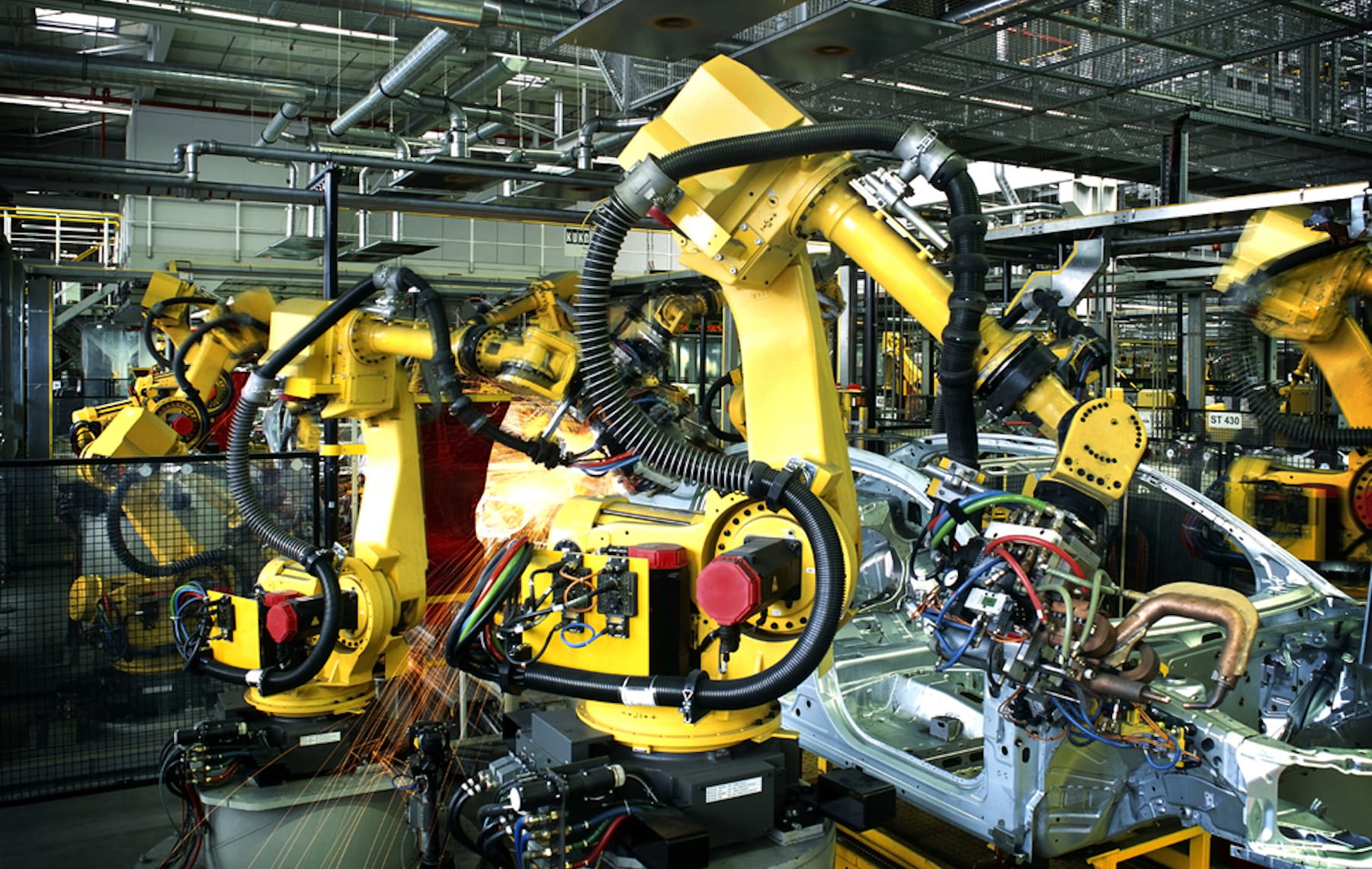 Yellow robotic articulating arms working in a factory